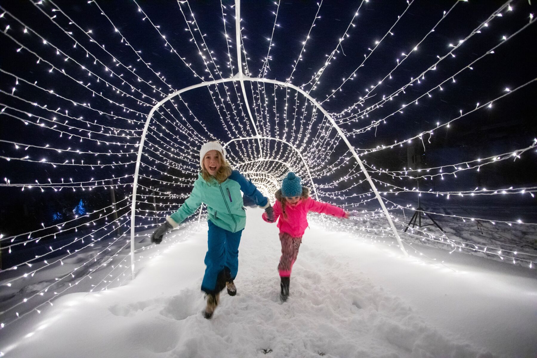 Young girls having fun in holiday light tunnel
